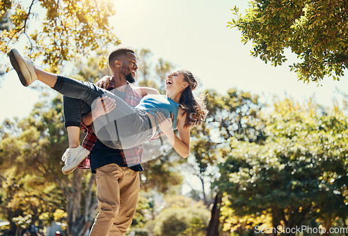 Image of Young interracial couple, park and man carrying woman on summer date in garden, sunshine fun or relax, love and care together. Happy couple, smile and diversity people in nature for relationship play