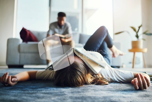 Image of Burnout, tired and student with book on face laying on floor after studying, reading and working on project. Education, university and woman exhausted, stressed and sad from college in living room