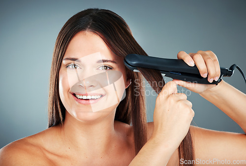 Image of Beauty, hair care and flat iron with a model woman in studio on a gray background to straighten her hair. Wellness, growth and straight with an attractive young female using a hair straightener