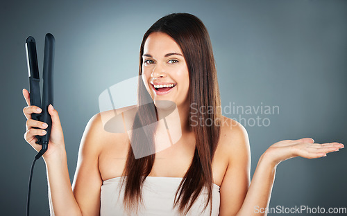 Image of Hair care, decision and woman with straight hair, product placement and marketing against a blue background in studio. Show, smile and portrait of a model advertising an iron for hair beauty