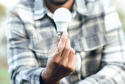 Image of Energy, nature and hand of man with light bulb for conservation innovation, engineering or creativity. Eco, bulb and idea of outdoor person for sustainability, green energy and development.