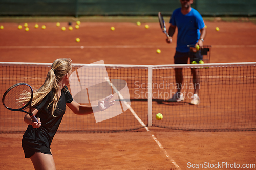 Image of A professional tennis player and her coach training on a sunny day at the tennis court. Training and preparation of a professional tennis player