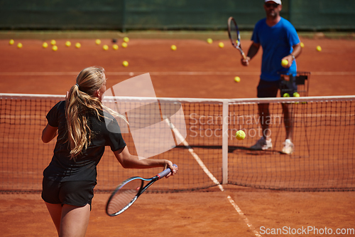 Image of A professional tennis player and her coach training on a sunny day at the tennis court. Training and preparation of a professional tennis player