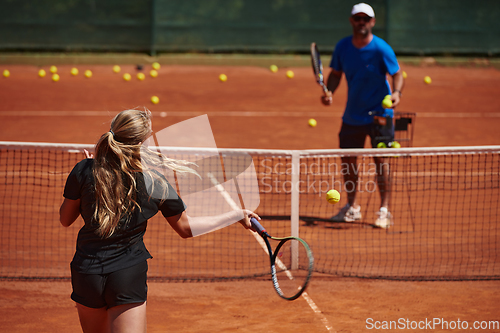 Image of A professional tennis player and her coach training on a sunny day at the tennis court. Training and preparation of a professional tennis player