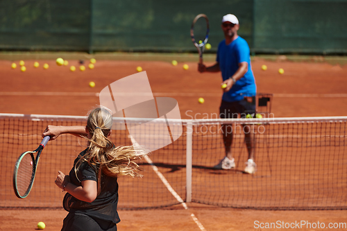 Image of A professional tennis player and her coach training on a sunny day at the tennis court. Training and preparation of a professional tennis player