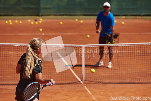 Image of A professional tennis player and her coach training on a sunny day at the tennis court. Training and preparation of a professional tennis player