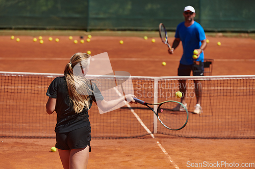 Image of A professional tennis player and her coach training on a sunny day at the tennis court. Training and preparation of a professional tennis player