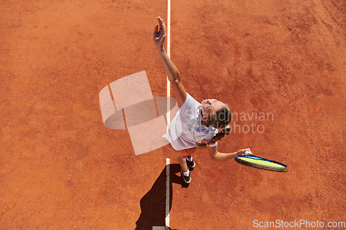 Image of Top view of a professional female tennis player serves the tennis ball on the court with precision and power