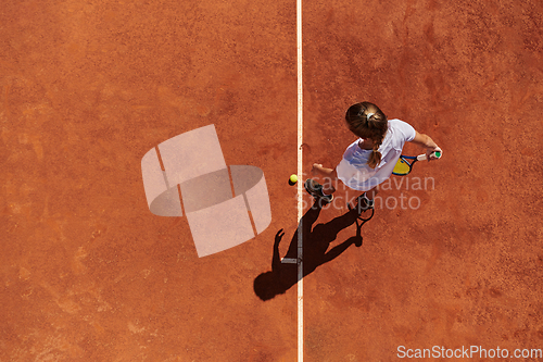 Image of Top view of a professional female tennis player serves the tennis ball on the court with precision and power