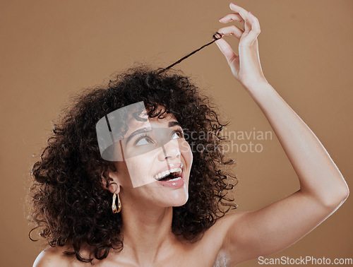 Image of Hair care, beauty and happy woman with afro in a studio for a health, clean and curly treatment. Wellness, hair style and young model holding strand of natural hair while isolated by brown background