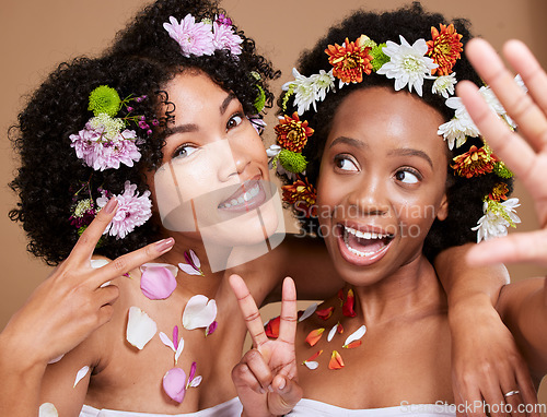 Image of Beauty, friends and flowers with a model black woman pair in studio on a brown background for skincare. Nature, luxury and relax with an attractive young female and friend posing for natural wellness