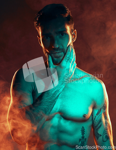 Image of Fitness, tattoo and man in studio for wellness, exercise and body goals with smoke, fire and danger aesthetic. Portrait, sexy and male model with misty atmosphere pose for training, muscle and power