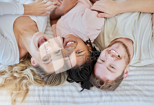 Image of Family, children and adoption with a mother, father and daughter lying on a bed in their home together. Portrait, love and kids with a man, woman and girl bonding in a house bedroom from above