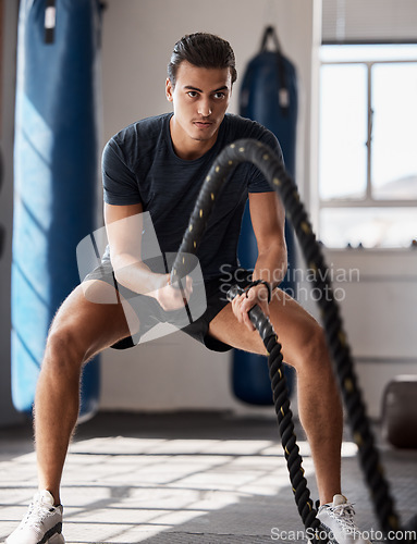 Image of Fitness, man and rope exercise, training and workout, muscle, energy and wellness in sports gym. Young body builder guy swinging battle ropes with energy, speed and power, challenge and performance