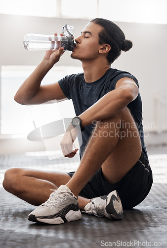 Image of Water bottle, fitness and gym man tired after a fitness training, exercise challenge and wellness goal with healthy diet or nutrition. Young sports person floor drinking water for healthy lifestyle