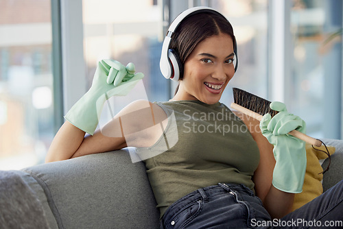 Image of Spring cleaning, singing and woman, portrait and music, headphones and fun in living room, lounge and sofa. Happy cleaner, karaoke and audio listening while dusting furniture in house, home and couch