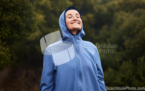 Image of Nature, happiness and woman with raincoat, smile and wellness standing in outdoor park. Peace, calm and girl enjoying natural environment, spring and fresh air hiking, walking and exercise in forest