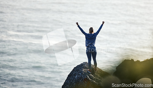 Image of Success, ocean and rock with woman hiking for travel, freedom or training vacation. Heath, workout and silhouette with girl athlete on landscape adventure for winner, motivation or exercise in nature