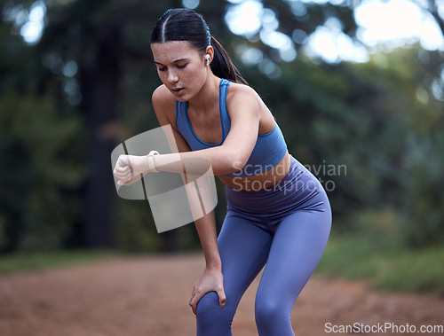 Image of Woman, earphones or fitness smart watch check in nature exercise, sustainability environment workout or forest trail training. Runner, sports athlete or person with clock time or health radio podcast