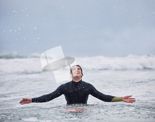 Image of Surfing, sports and man in ocean during rain enjoy nature, spring weather and swimming in waves. Happiness, raining and young male surfer in sea doing watersports for exercise, training and fitness
