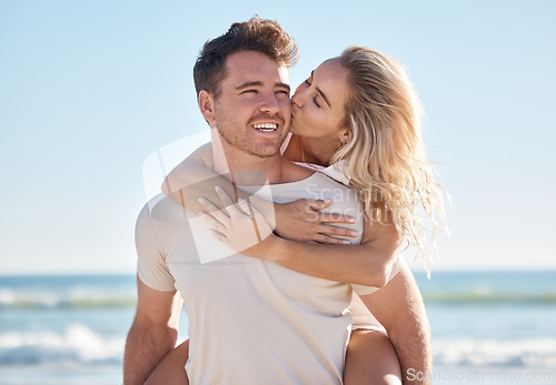 Image of Beach love, hug and couple kiss on romantic date, bonding getaway or outdoor nature adventure for peace, freedom and fun. Ocean sea, blue sky and man and woman piggyback on Sydney Australia holiday