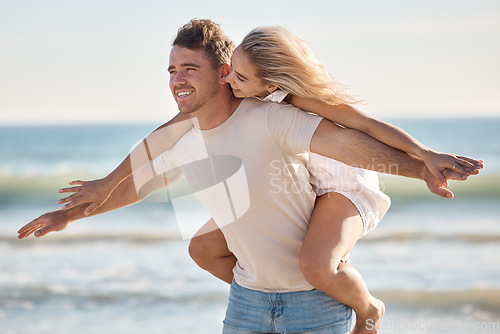 Image of Couple, freedom and love at the beach, together and piggyback on adventure with travel and ocean. Trust, relationship and man with happy woman, seaside vacation with arms out and care free.