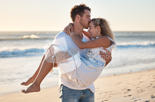 Image of Kiss, beach and man carrying woman for romantic sunset embrace on Australia holiday in summer. Couple, love and happy man holding partner with care, gratitude and respect on ocean walk.