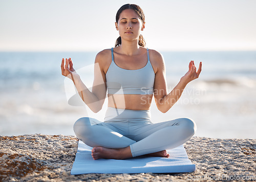 Image of Calm, beach and woman doing meditation exercise for zen, health and wellness of the mind and body. Spiritual, fitness and healthy girl in lotus pose doing yoga or pilates workout by the ocean or sea.