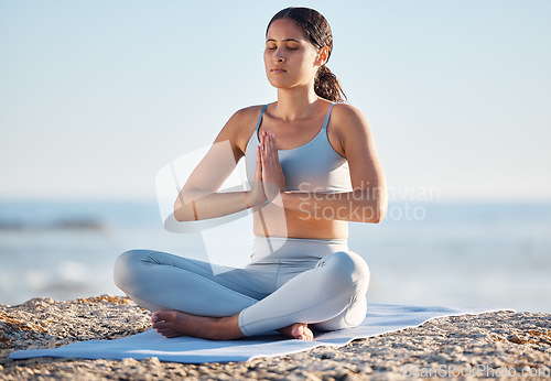 Image of Woman, yoga and beach for fitness, health and wellness with a mindfulness exercise in nature environment. Sea, pilates and fit female in lotus pose on a yoga mat for stress relief and mental health