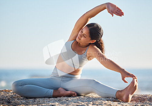 Image of Fitness, exercise and yoga at the beach with a young woman doing spiritual, chakra and zen workout on a rock by the sea. Aesthetic model outdoor for stretching, mindfulness and wellness in nature