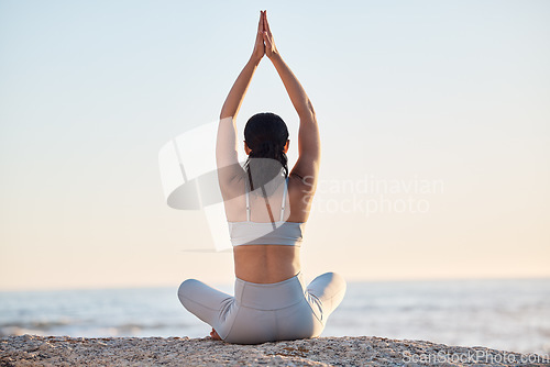 Image of Yoga, exercise and meditation at the beach with a woman in prayer position for zen, calm and balance while doing chakra workout for peace. Female at the ocean for mindfulness and spiritual training