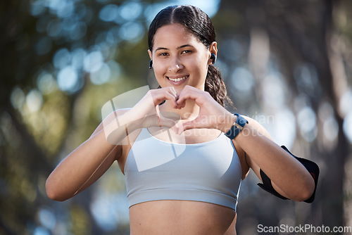 Image of Fitness portrait, heart hands and woman in nature with sign for affection or love emoji outdoors. Health, wellness and female athlete in park with hand symbol for support while preparing for training