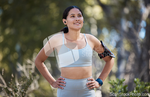 Image of Woman, earphones and fitness arm band in nature park break, garden or sustainability environment for exercise, training or workout. Smile, happy or resting runner listening to music or health podcast