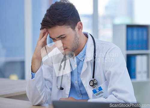 Image of Stress, headache and doctor with burnout sitting at his desk feeling depressed with in pain in hospital. Mental health, medicine and healthcare with frustrated male gp or physician feeling overworked