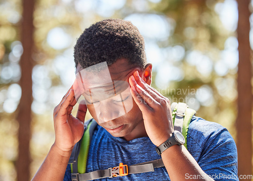 Image of Headache, stress hiking with a black man athlete holding his temples in pain while walking in the forest. Nature, fitness and migraine with a male hiker in the woods for exercise or training