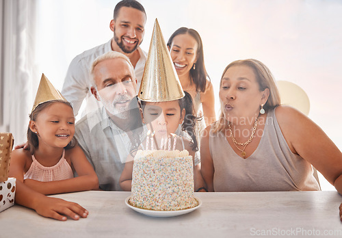 Image of Birthday, family and girl blowing candles on cake with party hats, parents and grandparents in home. Happiness, big family and happy young child make a wish on festive celebration and birthday party