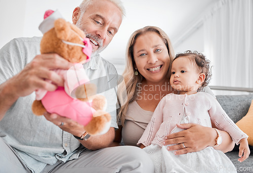 Image of Mature, couple and baby with a toy while babysitting grand daughter with love, care and affection for fun playing. Caring, living room and grandfather, grandmother and child bonding with teddybear