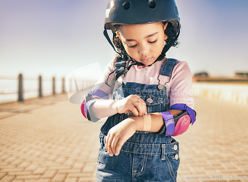 Image of Cycling injury, arm bandage and child in street with bruise after fall or accident. First aid, bandaid and hurt city girl with safety helmet after playing, sports or fitness exercise alone on road.