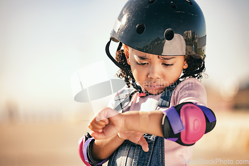 Image of Cycling injury, child and pain from a bike accident outdoor feeling stress and sadness. Young girl and summer cyclist or skating activity with a helmet and safety gear with arm bruise problem
