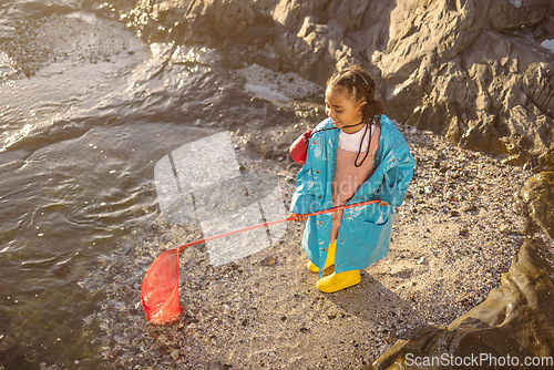 Image of Fishing, net and girl on an adventure at the beach with smile, happy and travel by the ocean in Spain. Nature, playful and child catching rocks by the sea on holiday for peace, relax and happiness