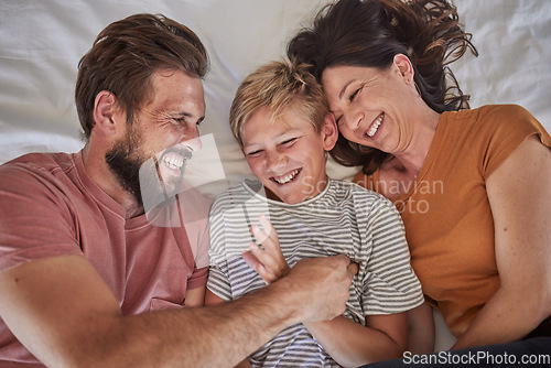 Image of Top view, parents or boy bonding in tickle game on house, family home or hotel bed in trust, love or security. Smile, happy man or laughing woman and son, comic child or preteen kid in funny activity
