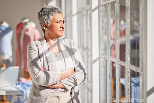 Image of Woman, thinking and arms crossed at office window for vision, planning work or fashion startup idea motivation. Clothes design manager, creative leader and stratergy dream or workplace inspiration