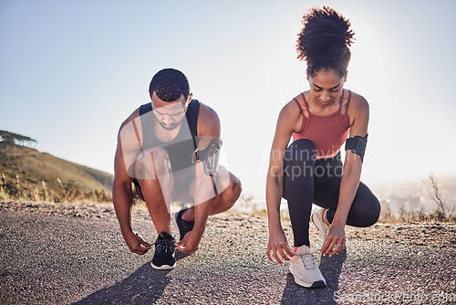 Image of Fitness couple, running shoes and exercise on a road outdoor for cardio workout and training together for health and wellness. Black woman and man tying shoelace or sneakers for a agile run