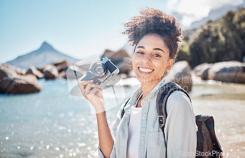 Image of Travel, beach and camera with a black woman tourist taking a photograph by the sea or ocean water in summer. Nature, portrait or photographer with a female outdoor on holiday or vacation by the coast