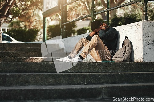 Image of Sad, depression and black man with anxiety at college, stress and headache from education on the stairs at campus. Depressed, frustrated and student with a mental health problem crying at university