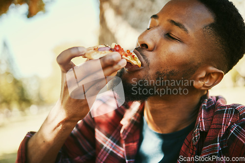Image of Fast food, hungry and black man eating pizza for delicious and yummy lunch break in park. Gen z, food and hunger of young person enjoying carbs pizza slice meal with satisfied face.