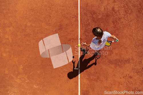 Image of Top view of a professional female tennis player serves the tennis ball on the court with precision and power