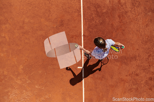 Image of Top view of a professional female tennis player serves the tennis ball on the court with precision and power