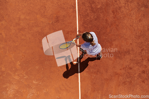 Image of Top view of a professional female tennis player serves the tennis ball on the court with precision and power