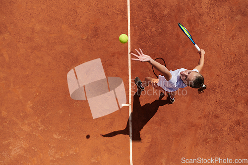 Image of Top view of a professional female tennis player serves the tennis ball on the court with precision and power